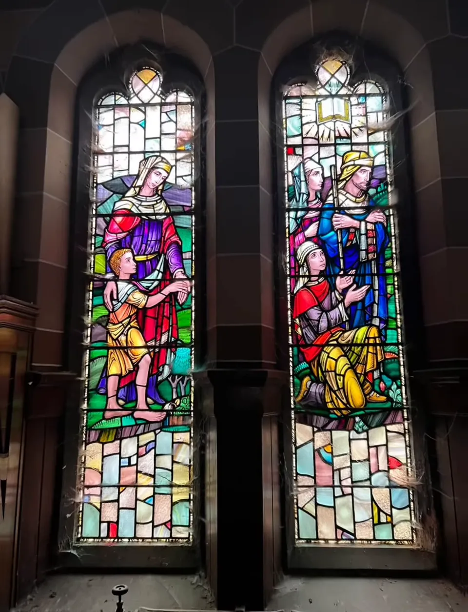 Two tall stained-glass windows showing figures in rich reds, blues and greens