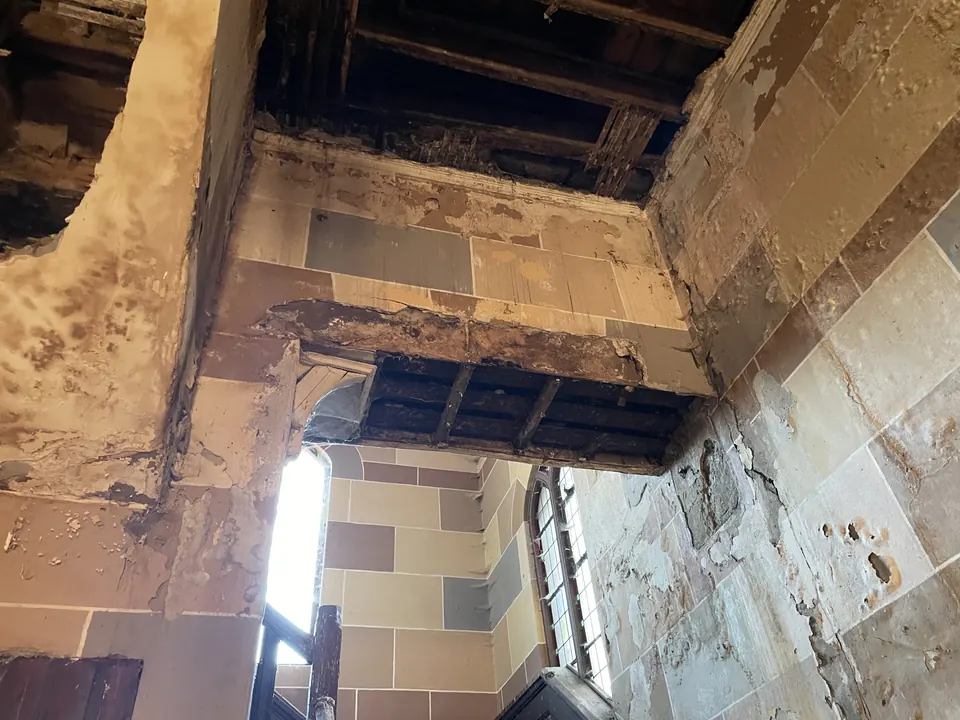 Damaged ceiling beams open to the roof