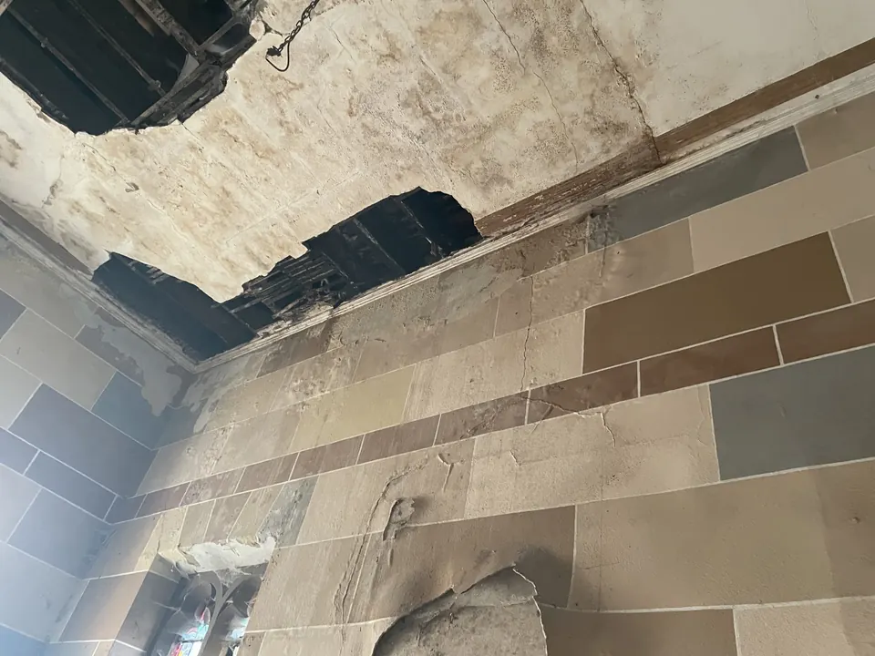 A water-stained ceiling with fallen plaster inside the empty building