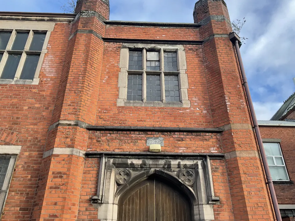 The red-brick hall front with its arched stone doorway