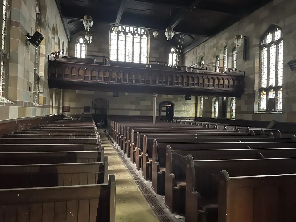 The nave from the gallery: rows of pews beneath tall windows