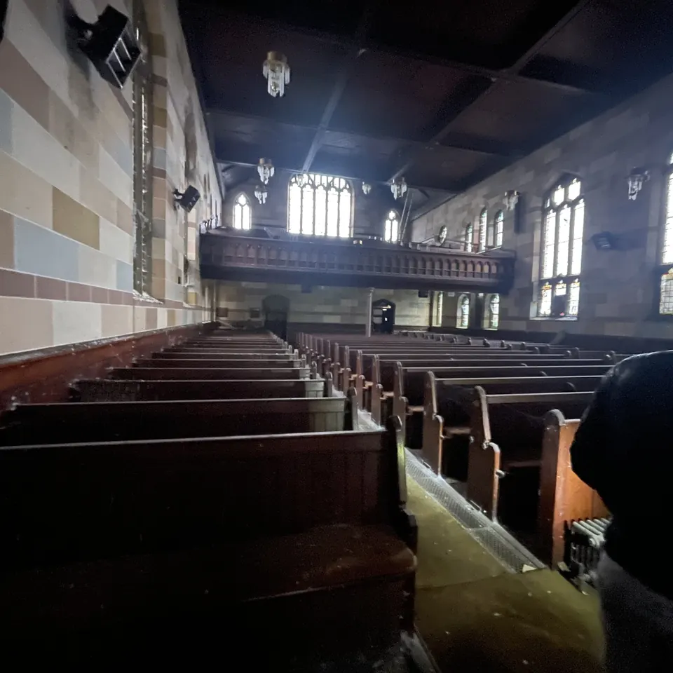 The nave today: empty pews beneath tall windows and the gallery